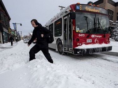 A man crosses a snowbank after getting off an OC Transpo bus in Ottawa's Glebe neighbourhood during a winter storm on Wednesday, Feb. 13, 2019. The storm, which began on Tuesday afternoon, is expected to bring 30-40 centimetres of snow by Wednesday. All Ottawa-area schools are closed and classes were cancelled for a 24 hour period at the University of Ottawa and Carleton University.