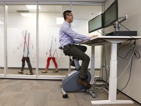 Ryan Wong works while riding a stationary bike at the Public Service Commission in Gatineau in September 2018. The public service commission features stationary bike and treadmill desks, part of an active workstations pilot project now a few years in the making.