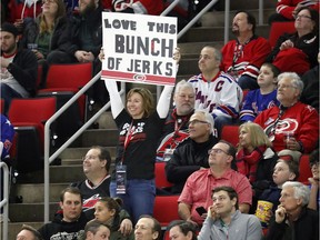 A Carolina Hurricanes fan holds a sign saying she loves this "Bunch of Jerks," a reference to the team during the second period of an NHL hockey game played against the New York Rangers in Raleigh, N.C., Tuesday, Feb. 19, 2019. Canadian broadcaster Don Cherry said the Hurricanes were a "Bunch of jerks," for the postgame celebrations that the team does when it wins at home. She also wears a tee shirt expressing the same feelings that the team has recently started selling in response to the comment.