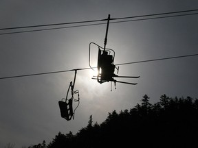 Skiers sit silhouetted on a chair lift.