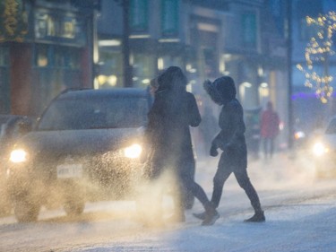 Pedestrians cross Bank Street at Third Avenue in the Glebe in the early stages of Tuesday's winter storm.