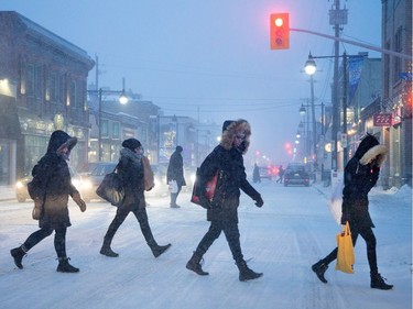 Pedestrians cross Bank Street in the Glebe as the storm starts Tuesday afternoon.