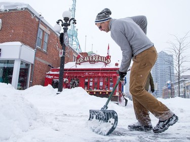 Nick Burak who works with Ottawa Markets, clears the walkway in front of the Byward Market building as the city crawls out from under a major winter storm which is possibly the biggest of the season.