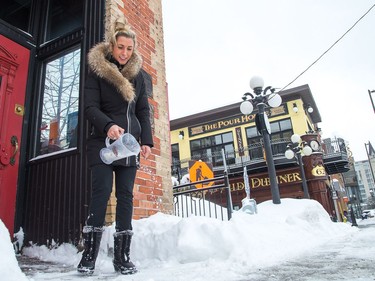 Chrystal Mullin uses a beer jug to spread salt in front of The Grand Pizzeria as the city crawls out from under a major winter storm which is possibly the biggest of the season.