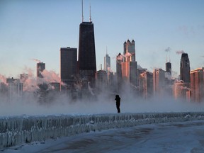 CHICAGO, ILLINOIS - JANUARY 31:  A man walks along an ice-covered break-wall along Lake Michigan while temperatures were hovering around -20 degrees and wind chills nearing -50 degrees on January 31, 2019