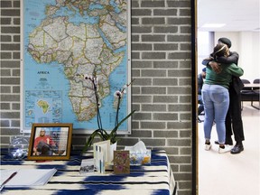 Family friend Kika Otiono is consoled after writing a message in a book of condolence that has been set up at the Institute of African Studies at Carleton University