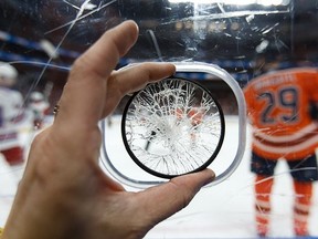Postmedia photographer Ian Kucerak holds up his camera filter, which absorbed the impact of an errant puck at a March 11 game between the Edmonton Oilers and the New York Rangers.