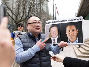 Louis Huang of Vancouver Freedom and Democracy for China holds photos of Canadians Michael Spavor and Michael Kovrig, who are being detained by China, outside British Columbia Supreme Court, in Vancouver, on March 6, 2019.