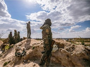 TOPSHOT - Fighters of the Syrian Democratic Forces (SDF) stand at a position overlooking the camp of Baghouz where remaining Islamic State (IS) group fighters and their families are holding out in the last position controlled by IS, awaiting to advance on them in the countryside of the eastern Syrian province of Deir Ezzor on March 17, 2019.