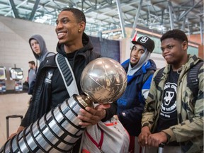 With Simon Chamberlain (from Left), Yasiin Joseph, and Alain Louis looking on, Marcus Anderson is all smiles while holding the trophy as the Carleton University Ravens mens basketball team return from Halifax after winning the national championship on Sunday.