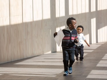 Enoch Sisay, 4, and Marken Sisay, 2, play in the shadows as they wait for their mom and sister to become Canadians during a special community citizenship ceremony held in the Great Hall at the National Gallery of Canada.