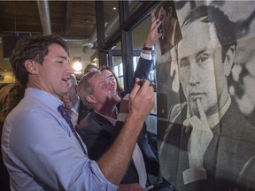 Justin Trudeau, not yet prime minister, signs a vintage poster of his father, former prime minister Pierre Trudeau, during a campaign stop in October 2015 in Ste-Therese, Que.