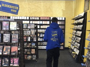 Employee Ryan Larrew reshelves movies that have been returned to the last Blockbuster store on the planet in Bend, Ore., in this Tuesday, March 12, 2019 photo. Larrew's sweatshirt advertises the store as the last one in America, but the store has ordered new sweatshirts and T-shirts saying it is the last Blockbuster on the planet. When a Blockbuster in Perth, Australia, shuts its doors for the last time on March 31, the store in Bend, Ore., will be the only one left on Earth, and most likely in the universe.