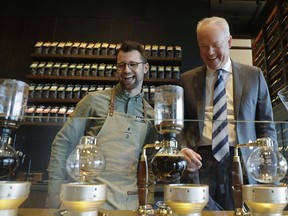 In this March 5, 2019, photo Kevin Johnson, right, CEO of Starbucks, makes coffee using a siphon method with barista Dylan George, left, as Johnson visits the company's Starbucks Reserve store in the company's headquarters building in Seattle's SODO neighborhood.