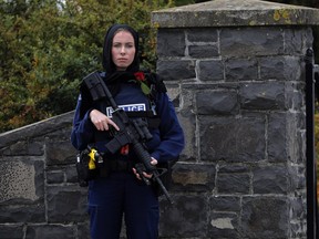 A police officer stands guard with a rose at the service for a victim of the Friday March 15 mosque shootings for a burial at the Memorial Park Cemetery in Christchurch, New Zealand, Thursday, March 21, 2019.