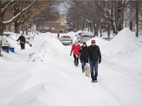 People walk in the ruts left by cars on a sidestreet in Ottawa's Glebe neighbourhood during a winter storm on Wednesday, Feb. 13, 2019.