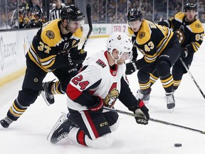 The Boston Bruins' Patrice Bergeron (37) and Danton Heinen (43) battle the Ottawa Senators' Oscar Lindberg (24) for the puck during the first period of an NHL hockey game in Boston, Saturday, March 9, 2019.