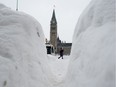 A woman is seen through the snowbanks on an unplowed sidewalk in downtown Ottawa, on Feb. 13.