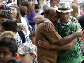 Two men embrace at the Botanical Gardens floral tribute during the "March for Love" following last week's mosque attacks in Christchurch, New Zealand, Saturday, March 23, 2019.