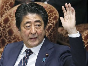 Japanese Prime Minister Shinzo Abe raises his hand.