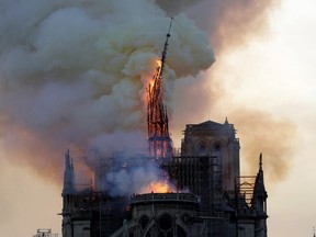 The steeple of the landmark Notre-Dame Cathedral collapses as the cathedral is engulfed in flames in central Paris on April 15, 2019. - A huge fire swept through the roof of the famed Notre-Dame Cathedral in central Paris on April 15, 2019, sending flames and huge clouds of grey smoke billowing into the sky. The flames and smoke plumed from the spire and roof of the gothic cathedral, visited by millions of people a year. A spokesman for the cathedral told AFP that the wooden structure supporting the roof was being gutted by the blaze.
