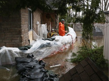 A man takes a break from removing the water from a flooded home on Boisé Lane that is being flooded by the Ottawa River in Cumberland,  April 26, 2019.