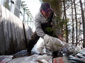 Rod Godman helps to sand bag his neighbour's property that is being flooded by the Ottawa River on Fraser Road in Aylmer.