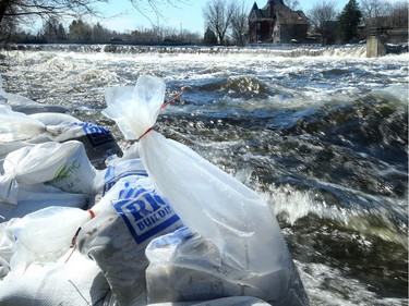 The Mississippi River roars past some sandbags in front of a home at the river's edge in Carleton Place. With the water only inches from the top of the break wall in town, residents fear any further rain. Julie Oliver/Postmedia