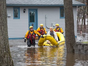 A woman is brought out of her home by Ottawa Fire as flood water rises in Constance Bay in April 2019.