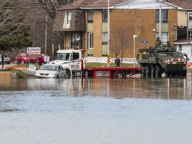 Members of the Canadian Forces Royal 22nd Regiment drive a Light Armoured Vehicle (LAV) along a flooded rue Saint Louis as a tow truck recovers a car in Gatineau, Quebec on April 22, 2019.