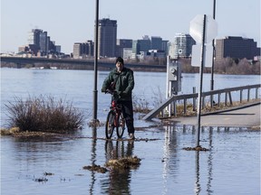 A cyclist stops at the submerged intersection of rue Jacques-Cartier and rue des Montgolfières in Gatineau on Monday.