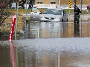 A man takes a look at a car that failed to get through rising flood waters along Rue Saint Louis in Gatineau, Quebec on April 22, 2019.