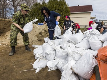 Members of the Canadian Forces Royal 22nd Regiment and area residents fill sand bags to protect against rising flood waters in Gatineau, Quebec on April 22, 2019.