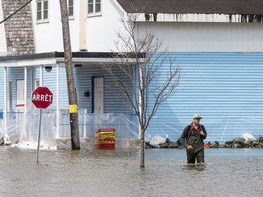 A man walks in hip waders along a flooded rue Saint Louis in Gatineau, Quebec on April 23, 2019.