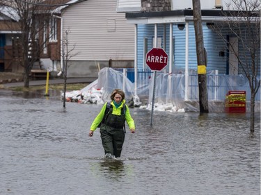 Lyne Lamache walks in hip waders along a flooded rue Saint Louis in Gatineau, Quebec on April 23, 2019.
