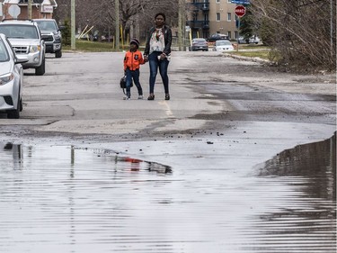 A woman and young boy are prevented from walking down a flooded rue Moreau in Gatineau, Quebec on April 23, 2019.