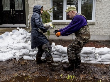 Marie Labelle and Rob Godman work together to build walls of sandbags to combat flooding at a friends home on Fraser Road in Gatineau on April 26, 2019.