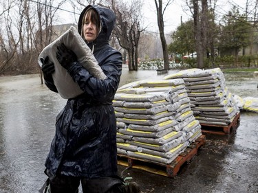 Marie Labelle carries sandbags to combat flooding at a friends home on Fraser Road in Gatineau on April 26, 2019.