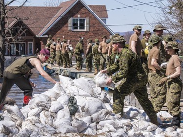 Members of the Canadian Armed Forces move sandbags to  combat flood waters in Cumberland on Sunday.