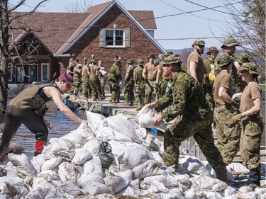 Members of the Canadian Armed Forces move sandbags to  combat flood waters in Cumberland on Sunday.