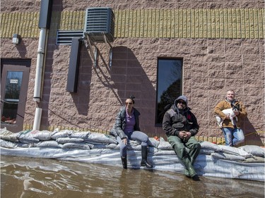Carine Aroneca, Steve Maisoneuve, Andre Guy, and dog "Louis" are staying with their business on Rue Saint-Louis  in the flooded Pointe-Gatineau neighbourhood of the city on Sunday.