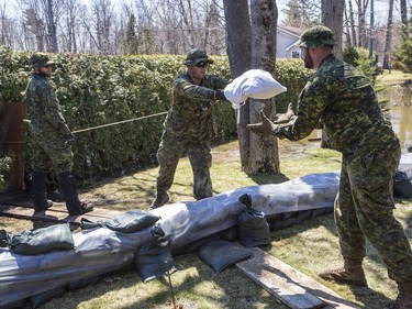 Members of the Canadian Armed Forces move sandbags to combat flood waters in Cumberland on Sunday.