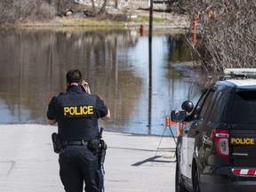 An O.P.P. officer takes photographs near where a man's body was discovered in flood water on Riverview Drive in Arnprior, Ontario on April 29, 2019.