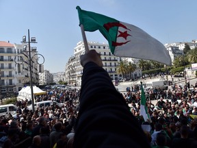 Algerians wave the national flag as they demonstrate to demand sweeping change to the country's whole political system, in Algiers on April 3, 2019, following the resignation of ailing leader Abdelaziz Bouteflika.