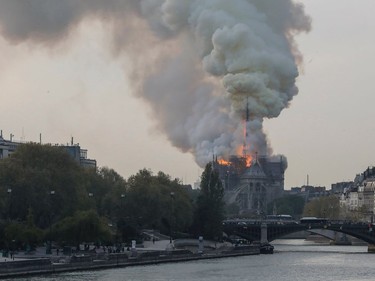 TOPSHOT - Smokes ascends as flames rise during a fire at the landmark Notre-Dame Cathedral in central Paris on April 15, 2019 afternoon, potentially involving renovation works being carried out at the site, the fire service said.