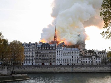TOPSHOT - Seen from across the Seine River, smoke and flames rise during a fire at the landmark Notre-Dame Cathedral in central Paris on April 15, 2019, potentially involving renovation works being carried out at the site, the fire service said.
