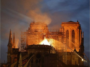 Firefighter douse flames billowing from the roof at Notre-Dame Cathedral in Paris on April 15, 2019. - A major fire broke out at the landmark Notre-Dame Cathedral in central Paris sending flames and huge clouds of grey smoke billowing into the sky, the fire service said. The flames and smoke plumed from the spire and roof of the gothic cathedral, visited by millions of people a year, where renovations are currently underway.