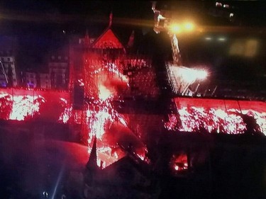 An image taken from a television screen shows an aerial view of the Notre-Dame Cathedral engulfed in flames on April 15, 2019, in the French capital Paris. - A huge fire swept through the roof of the famed Notre-Dame Cathedral in central Paris on April 15, 2019, sending flames and huge clouds of grey smoke billowing into the sky. The flames and smoke plumed from the spire and roof of the gothic cathedral, visited by millions of people a year. A spokesman for the cathedral told AFP that the wooden structure supporting the roof was being gutted by the blaze.