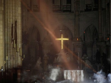 TOPSHOT - Smoke rises around the alter in front of the cross inside the Notre-Dame Cathedral as the fire continues to burn on April 16, 2019 in the French capital Paris. - A huge fire swept through the roof of the famed Notre-Dame Cathedral in central Paris on April 15, 2019, sending flames and huge clouds of grey smoke billowing into the sky. The flames and smoke plumed from the spire and roof of the gothic cathedral, visited by millions of people a year. A spokesman for the cathedral told AFP that the wooden structure supporting the roof was being gutted by the blaze.