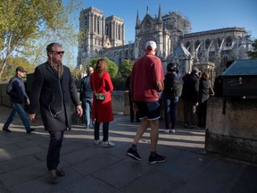 Passersby walk near the Notre-Dame de Paris Cathedral, in the aftermath of a fire that devastated much of the cathedral on Monday.